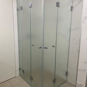 מקלחון זכוכית עם דלתות מתכת בחדר אמבטיה