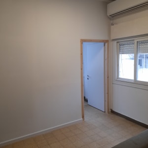 קיר גבס לבן עם דלת עץ פתוחה