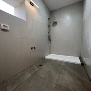 חדר רחצה עם מקלחון חדש, אריחים אפורים, תאורה מותקנת