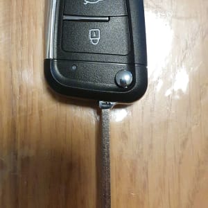 מפתח רכב עם שלושה כפתורים על שולחן עץ