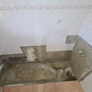 שיפוץ אמבטיה עם קירות חשופים וריצוף חלקי