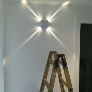 סולם עץ מתחת לגוף תאורה על קיר לבן