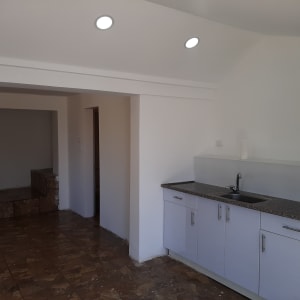 מטבח עם ארונות לבנים וכיור, רצפת שיש חומה