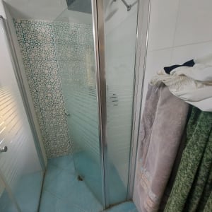 מקלחון זכוכית עם ראש מקלחת מרובע וקיר מעוצב