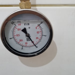 מד לחץ עם חיבור מתכת על קיר לבן