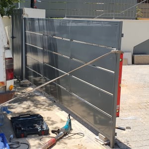 שער מתכת אפור פתוח עם חבל קשור לרכב