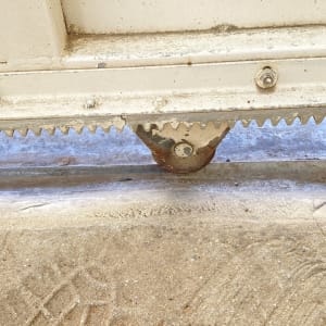 תקריב של גלגל, מסילה ופס שיניים בתחתית שער חשמלי הזזה