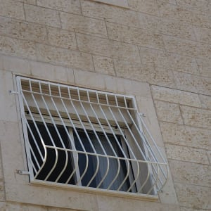 סורגי מתכת לבנים על חלון בניין אבן