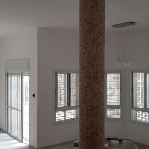 קיר לבן עם חלונות, דלי צבע ומקדחה על הרצפה