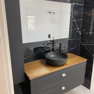 כיור שחור על משטח עץ בחדר אמבטיה משופץ