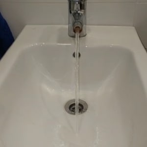 ברז מים זורמים בכיור לבן