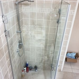 מקלחון עם בקבוקי שמפו וסבון על הרצפה