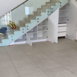 ארונות לבנים מתחת למדרגות עם דלתות פתוחות