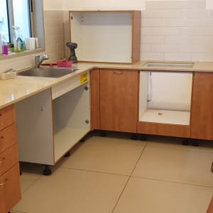 מטבח בשיפוץ עם ארונות פתוחים ומקדחה על השיש