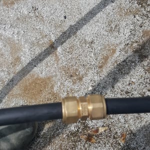 חיבור צינור פלסטיק עם מחבר מתכת על רקע בטון