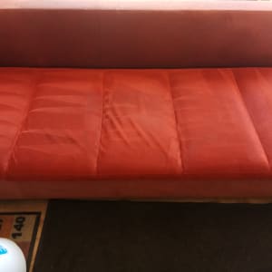 ספה אדומה עם סימני ניקוי, דלי כחול בצד