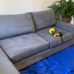 ספה אפורה עם מכונת ניקוי על יריעת פלסטיק כחולה