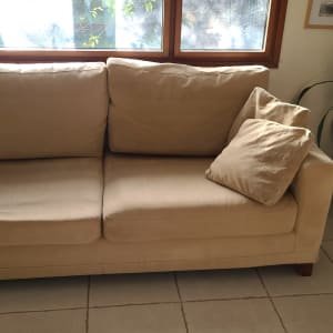 ספה בהירה עם כריות בסלון מואר