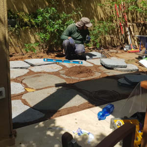 אדם עובד בגינה עם אבנים, עפר וכלי עבודה