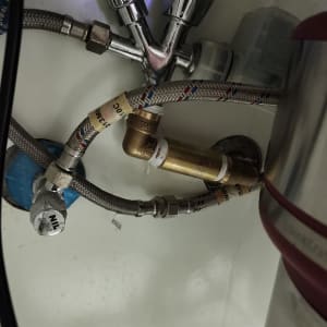 צינורות מתכת וברזים מתחת לכיור מטבח