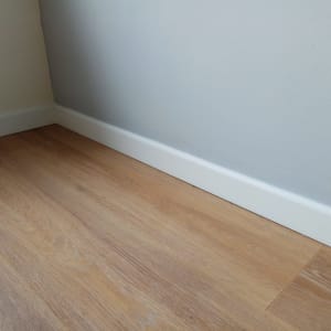 רצפת פרקט עץ עם פנל לבן על הקיר