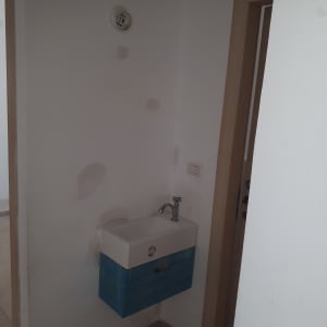 קיר עם תיקוני צבע ליד כיור קטן