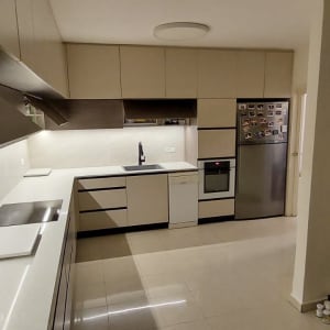 מטבח מודרני עם ארונות לבנים, כיור ותנור נירוסטה