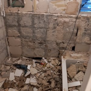 שיפוץ חדר עם קירות חשופים והריסות על הרצפה