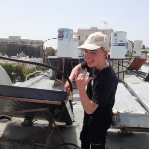 אדם ליד דוד שמש על גג עם צינורות