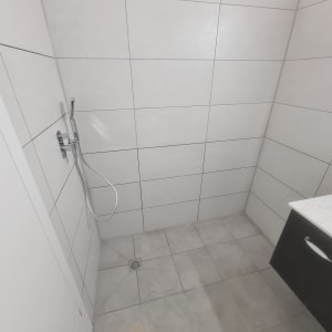 חדר אמבטיה עם אריחים חדשים ומקלחת מותקנת