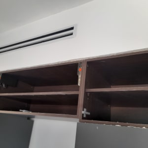 ארון פתוח עם מדפים מעץ מתחת לפתח מיזוג אוויר