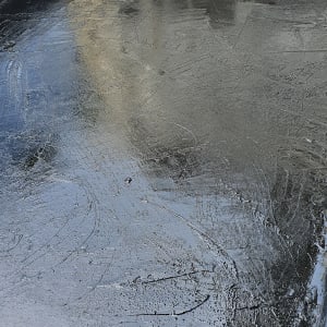 משטח אטום בזפת שחורה עם קיר מתקלף ברקע