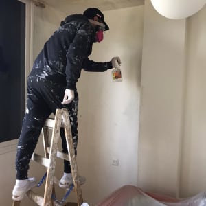 אדם מרסס חומר איטום על קיר בעזרת תרסיס