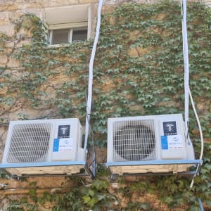 שני מזגנים מותקנים על קיר עם צמחייה מטפסת