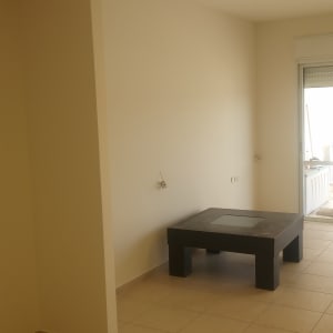 קיר צבוע בלבן עם שולחן כהה בחדר ריק