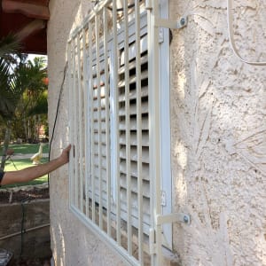 סורג מתכת לבן מותקן על חלון קיר חיצוני