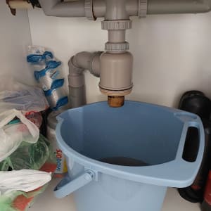 צנרת מתחת לכיור עם דלי כחול