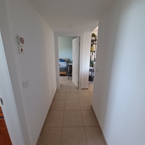 מסדרון עם קירות לבנים ורצפת אריחים