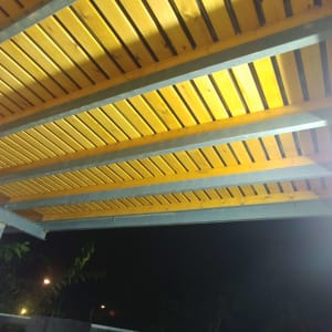 פרגולה מעץ עם קורות מתכת בגינה בלילה