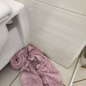 מגבת סגולה על רצפת חדר אמבטיה ליד אסלה