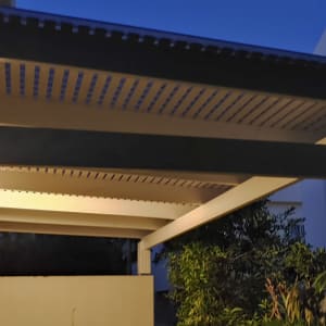 פרגולה מעץ עם תאורה בחצר בשעת ערב