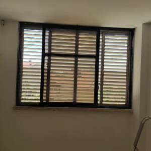 חלון עם תריסים סגורים וסולם בצד ימין