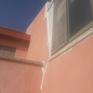 קיר ורוד עם איטום לבן סביב חלון