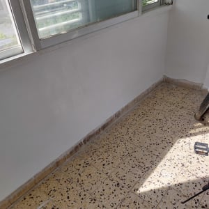 קיר צבוע בלבן עם רצפת אריחים מנוקדת