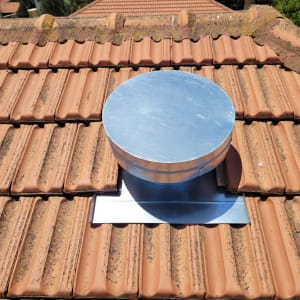 צינור מתכת עגול על גג רעפים אדומים