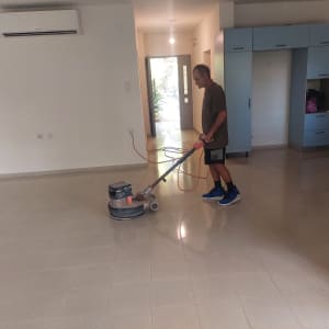 אדם מנקה רצפה עם מכונת פוליש בחדר ריק