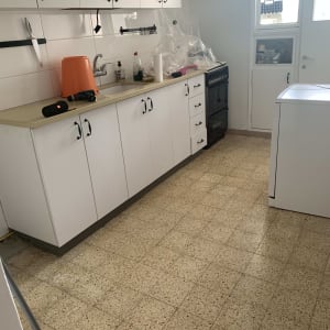 מטבח עם ארונות לבנים ורצפת פרקט בהירה