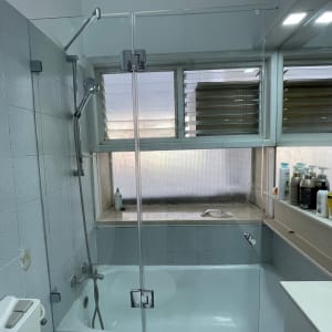 מקלחת עם אמבטיה, דלת זכוכית ומוצרים על המדף