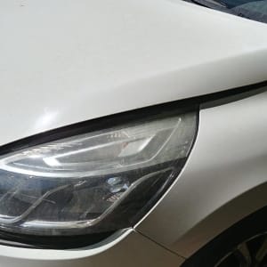 חזית רכב לבן עם פנס קדמי וכנף