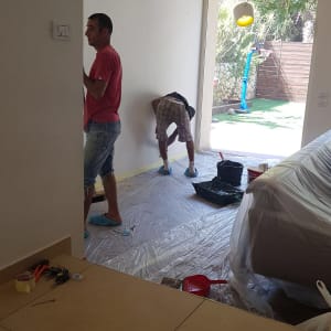 שני אנשים עובדים על קיר, יריעות פלסטיק על הרצפה